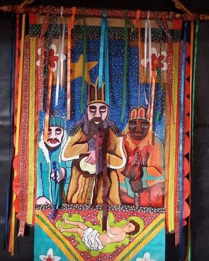 Banner with three kings under a star and the Child Jesus lying below, with colorful ribbons hanging