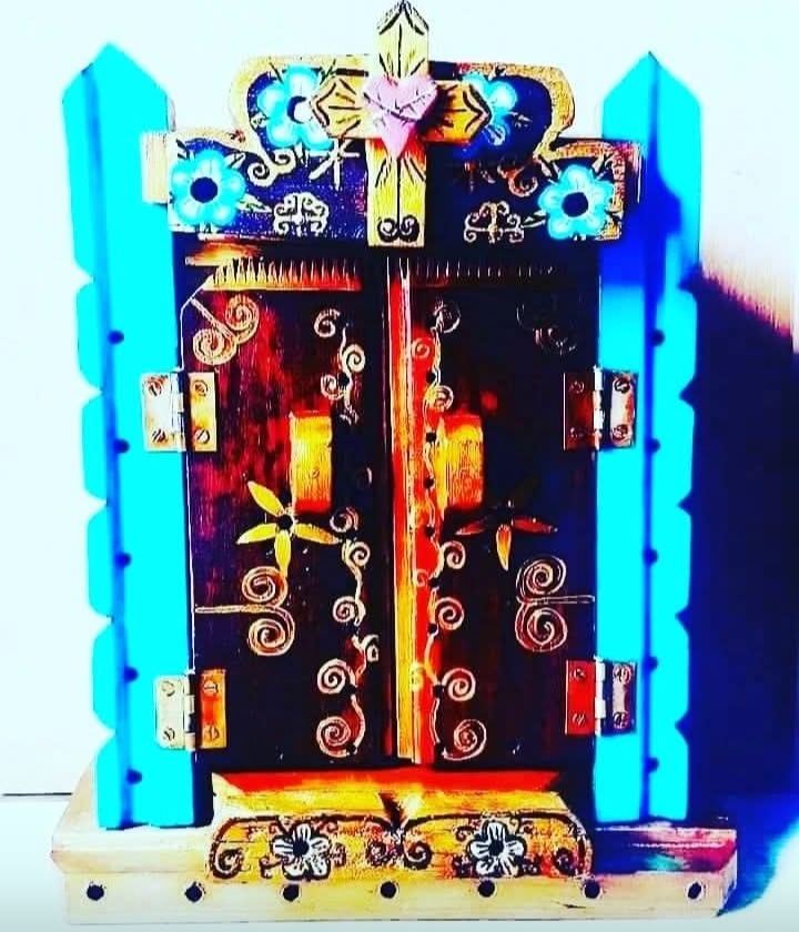 Closed oratório between turquoise pillars, with golden spirals and flowers on the doors and a heart with a cross on top