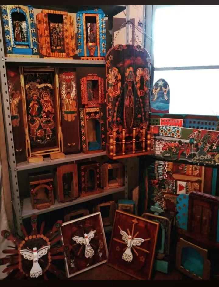 Estante do ateliê cheia de oratórios e quadros de anjos